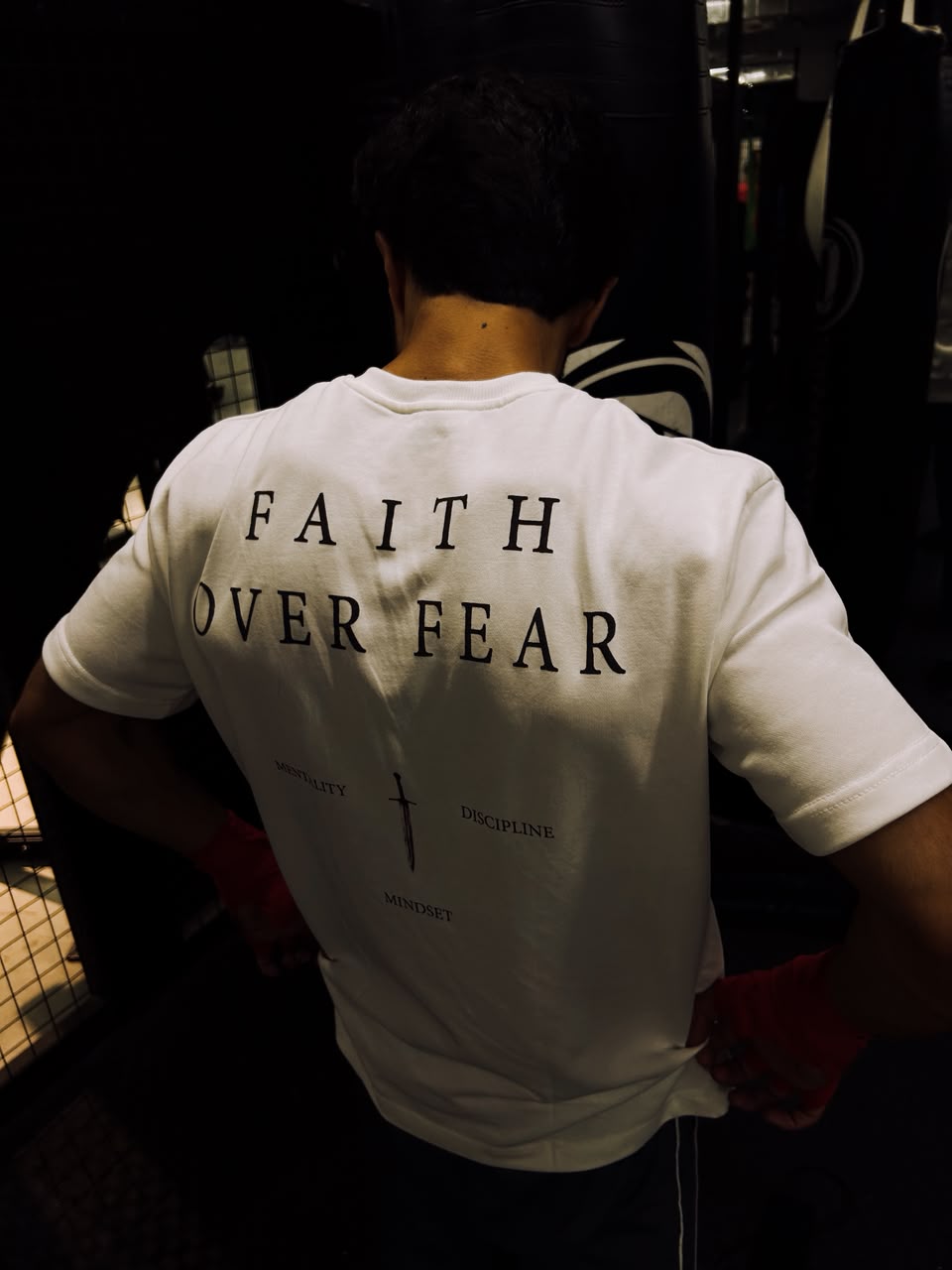 White tee in the gym beside the punching bags