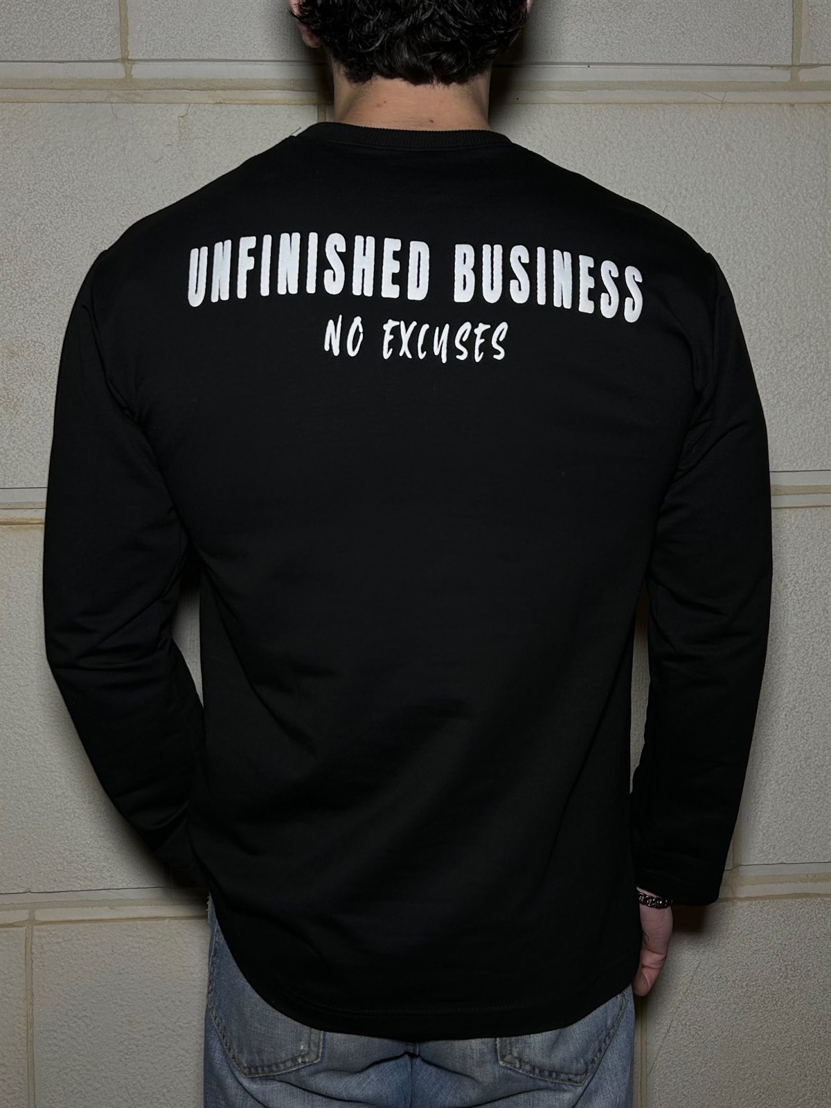 The back of the black Unfinished Business long sleeve, UNFINISHED BUSINESS over NO EXCUSES